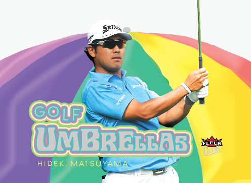 Hideki Matsuyama holding his club in front of a large purple, green, yellow and red umbrella.